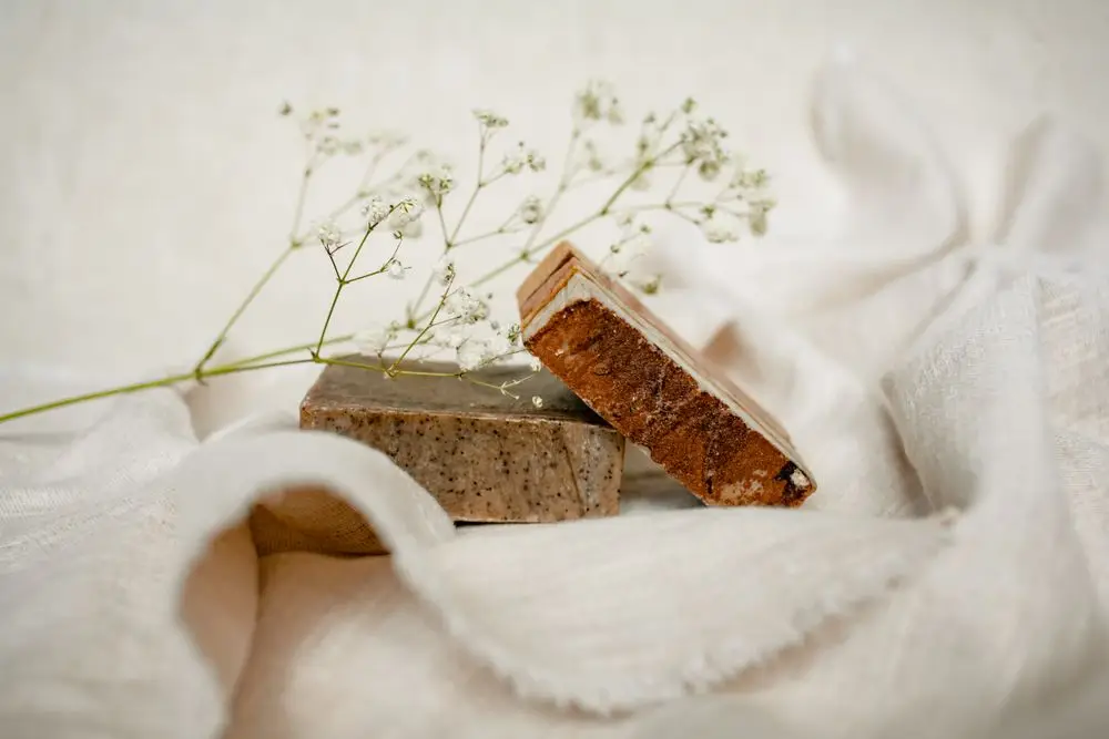 Håndlaget såpe på lyst tekstil med tørket plante